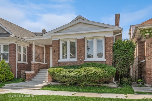 view of front of house with a chimney and brick siding