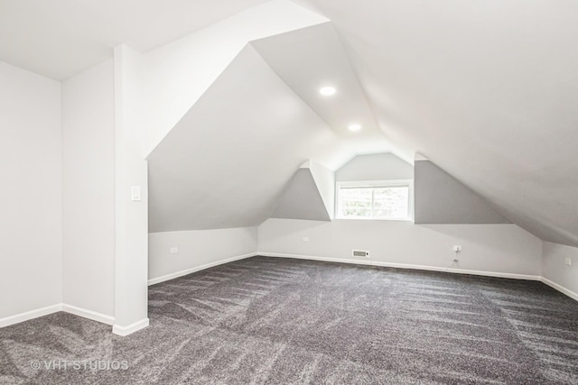 additional living space featuring baseboards, visible vents, lofted ceiling, dark carpet, and recessed lighting