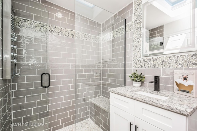 bathroom featuring a stall shower, decorative backsplash, tile walls, and vanity