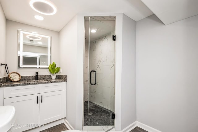 bathroom featuring a marble finish shower, vanity, and baseboards