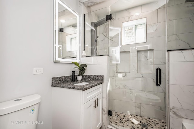 bathroom featuring a shower stall, toilet, and vanity