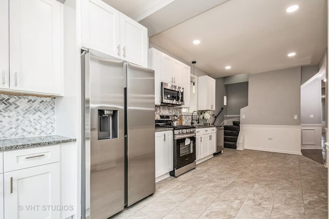 kitchen featuring appliances with stainless steel finishes, stone counters, backsplash, and white cabinets