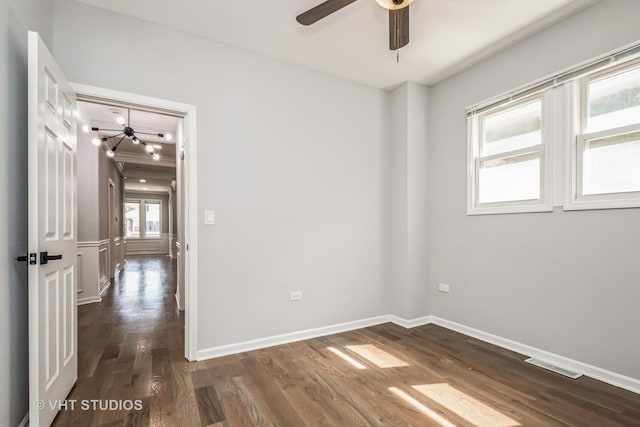 spare room with baseboards, visible vents, ceiling fan, and dark wood-type flooring