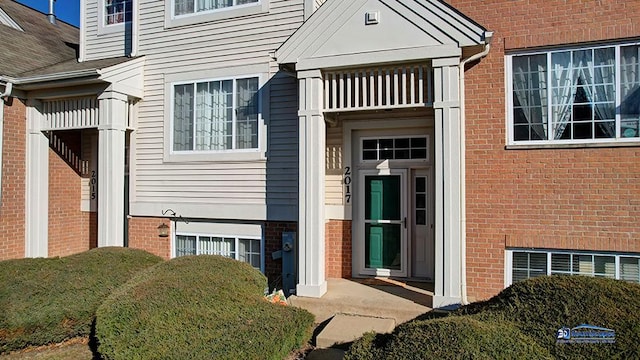 property entrance featuring a balcony and brick siding