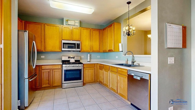 kitchen featuring light countertops, light tile patterned floors, appliances with stainless steel finishes, hanging light fixtures, and a sink