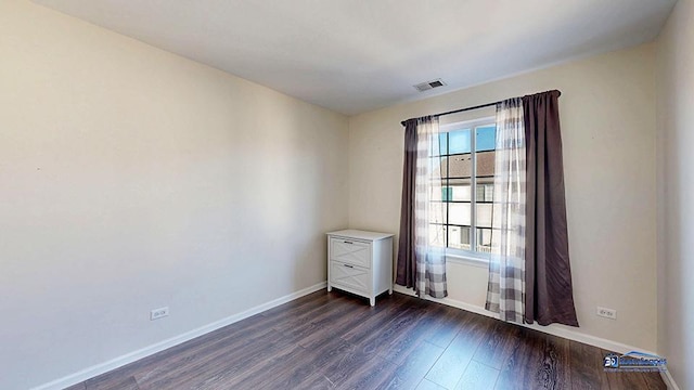 unfurnished room featuring visible vents, baseboards, and dark wood-style flooring