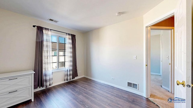 spare room featuring dark wood-style floors, visible vents, and baseboards