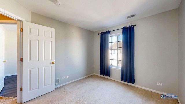 carpeted empty room featuring baseboards and visible vents