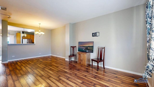 living area with a chandelier, visible vents, baseboards, and hardwood / wood-style floors