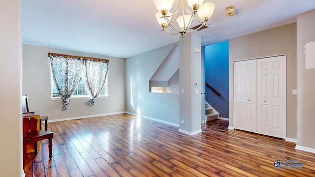 additional living space featuring a chandelier, baseboards, wood finished floors, and stairway