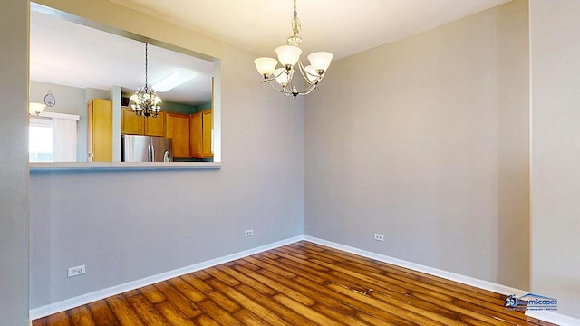 unfurnished room featuring baseboards, an inviting chandelier, and dark wood finished floors