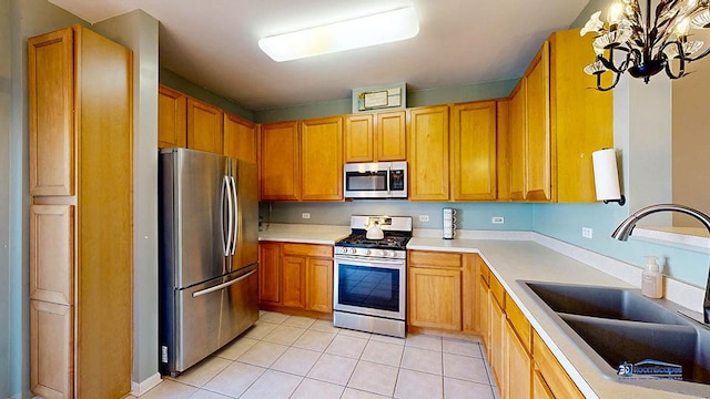 kitchen featuring light countertops, appliances with stainless steel finishes, an inviting chandelier, light tile patterned flooring, and a sink