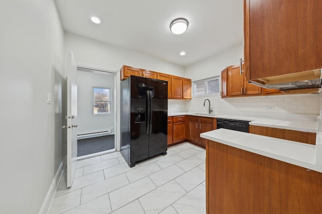 kitchen featuring backsplash, baseboard heating, light countertops, black appliances, and a sink