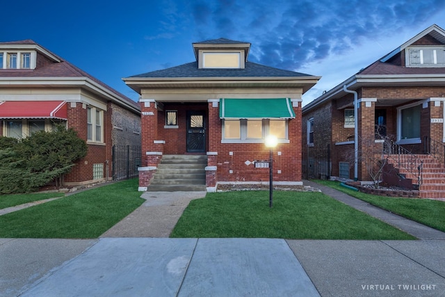 bungalow featuring a front yard, brick siding, and roof with shingles