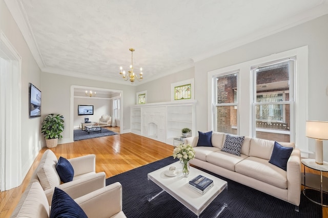 living area featuring baseboards, ornamental molding, wood finished floors, and a notable chandelier