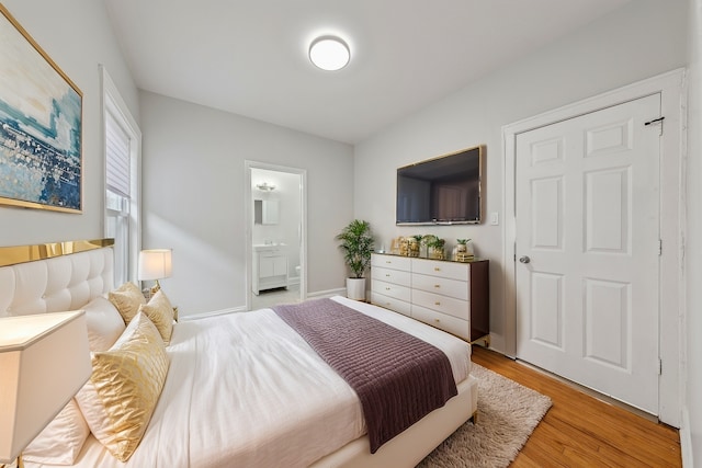 bedroom featuring ensuite bath and light wood-style flooring