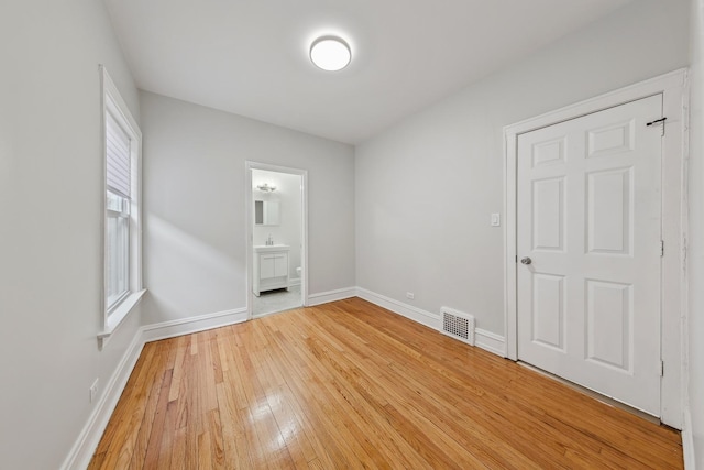 spare room with baseboards, a sink, visible vents, and light wood-style floors