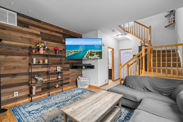 living area featuring stairway, wood finished floors, visible vents, and wooden walls