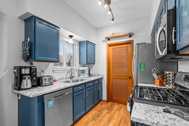 kitchen featuring stainless steel appliances, a sink, light wood-style floors, blue cabinetry, and rail lighting