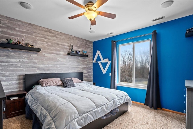 bedroom with an accent wall, carpet, visible vents, and baseboards