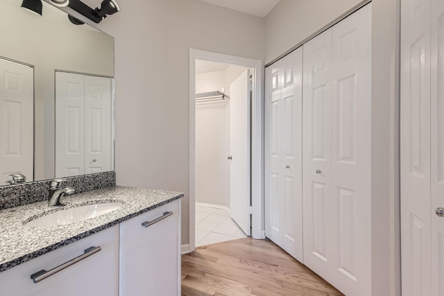 bathroom with a closet, wood finished floors, and vanity