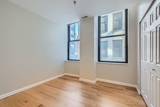 spare room with light wood-style floors, visible vents, and baseboards