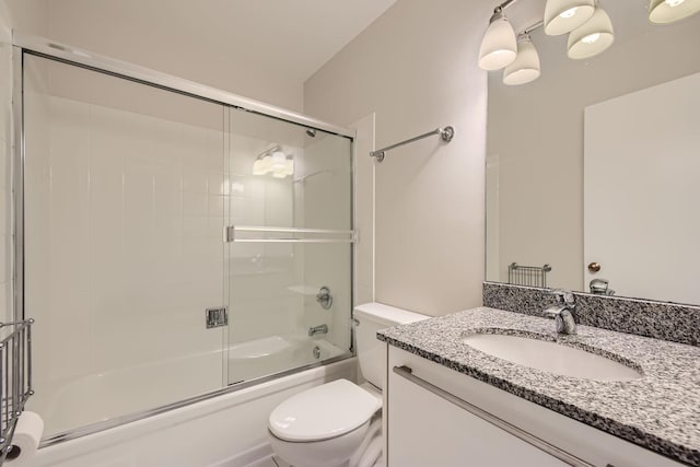 bathroom with enclosed tub / shower combo, vanity, and toilet