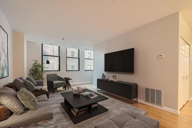 living area featuring light wood finished floors, visible vents, and baseboards