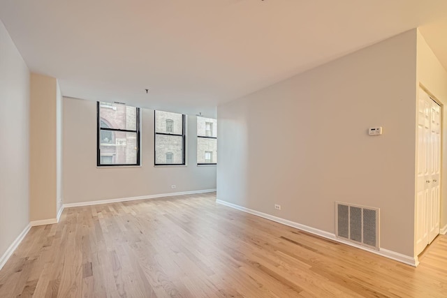 empty room with baseboards, visible vents, and light wood-style floors