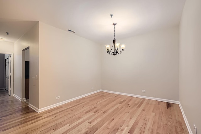 unfurnished room featuring baseboards, light wood finished floors, visible vents, and an inviting chandelier