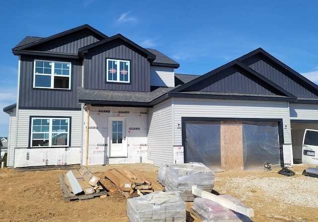 view of front of home featuring roof with shingles, board and batten siding, and an attached garage