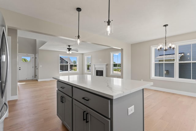 kitchen with light wood finished floors, a kitchen island, open floor plan, gray cabinets, and a fireplace