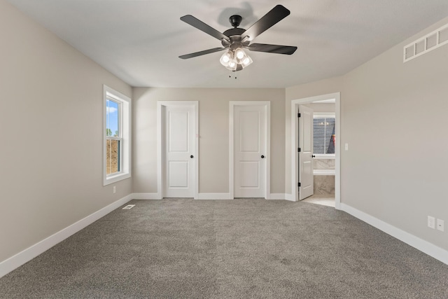 unfurnished bedroom featuring visible vents, ensuite bath, carpet floors, baseboards, and ceiling fan