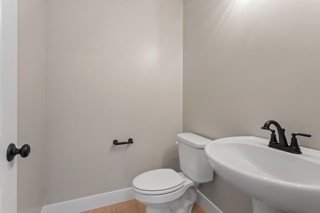 bathroom with a sink, baseboards, toilet, and wood finished floors