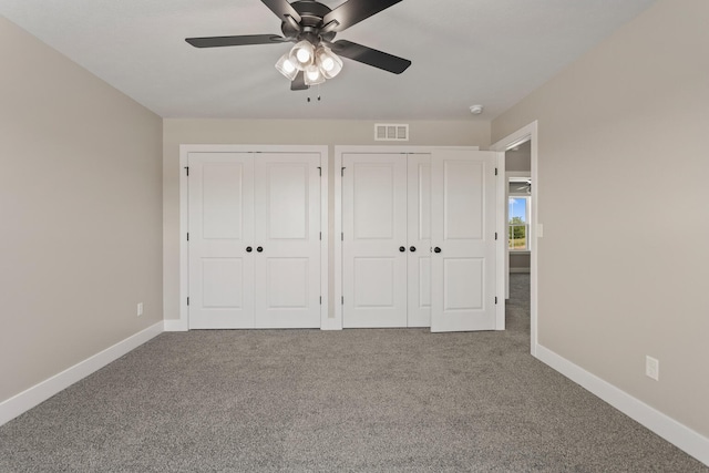 unfurnished bedroom featuring visible vents, baseboards, carpet floors, ceiling fan, and two closets