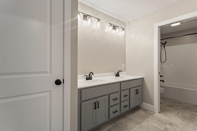 full bath with a sink, toilet, marble finish floor, and double vanity