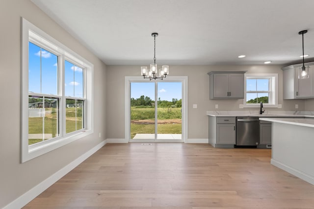 kitchen with baseboards, gray cabinets, light countertops, dishwasher, and light wood-type flooring