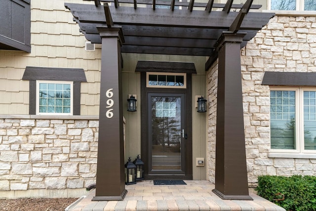 doorway to property with a pergola and stone siding