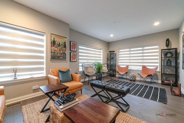 living room with wood finished floors, visible vents, and baseboards