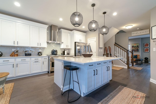 kitchen featuring white cabinets, appliances with stainless steel finishes, and wall chimney range hood