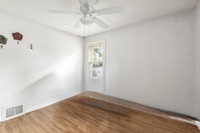 spare room with visible vents, ceiling fan, a textured ceiling, and wood finished floors