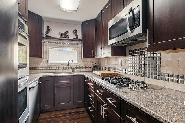 kitchen featuring dark wood finished floors, appliances with stainless steel finishes, a sink, and dark brown cabinetry