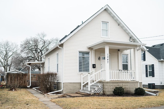 bungalow featuring covered porch, cooling unit, and a front yard