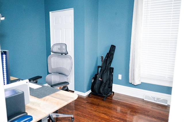 office area featuring baseboards, visible vents, and wood finished floors