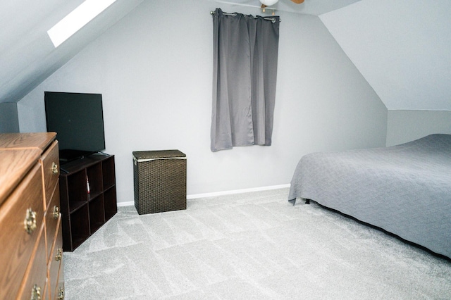 bedroom featuring vaulted ceiling with skylight, baseboards, and carpet flooring