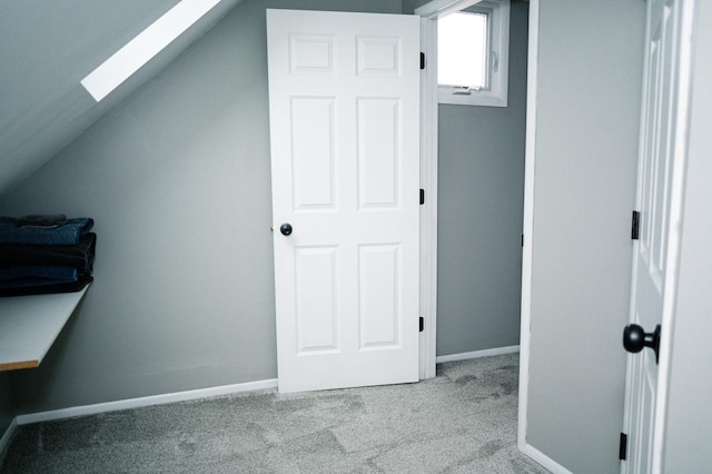 additional living space with carpet floors, vaulted ceiling with skylight, and baseboards