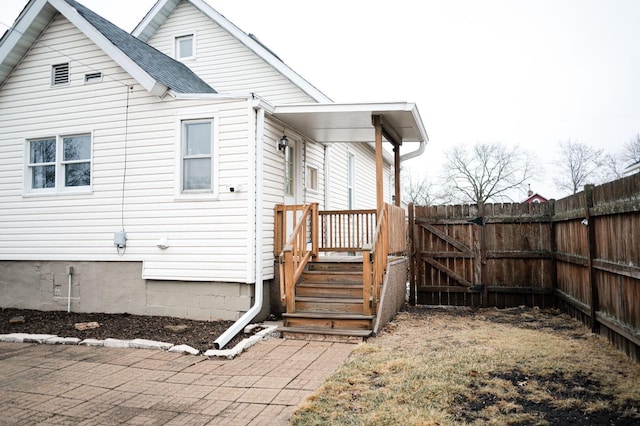 back of house featuring roof with shingles, fence, and a gate