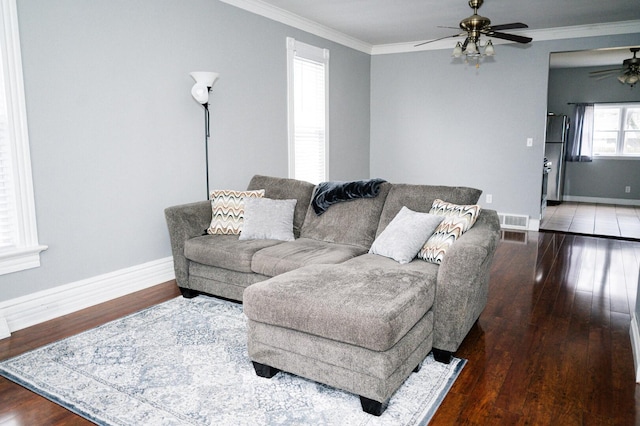 living room with wood finished floors, visible vents, and crown molding