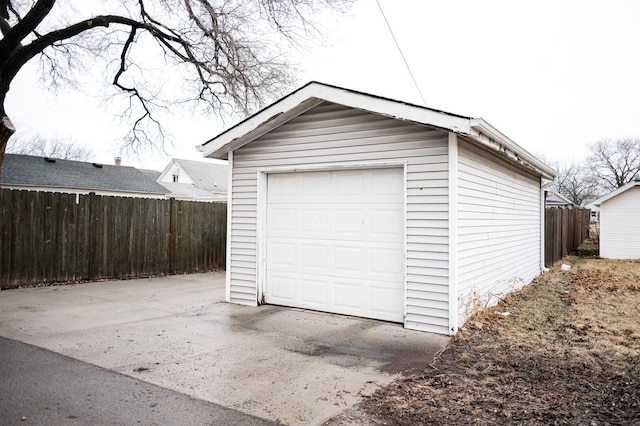 detached garage with concrete driveway and fence