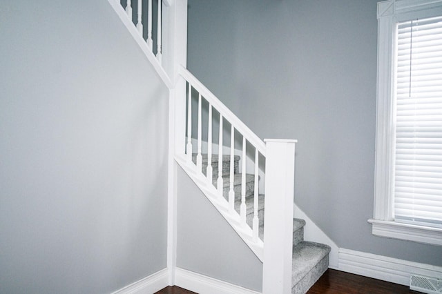 stairway featuring baseboards, visible vents, and wood finished floors